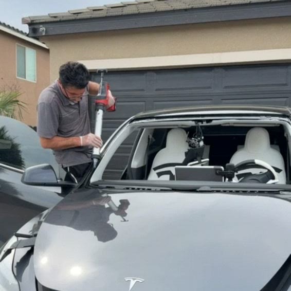 A Safety Prime technician setting a windshield into a Tesla on the customer’s own driveway
